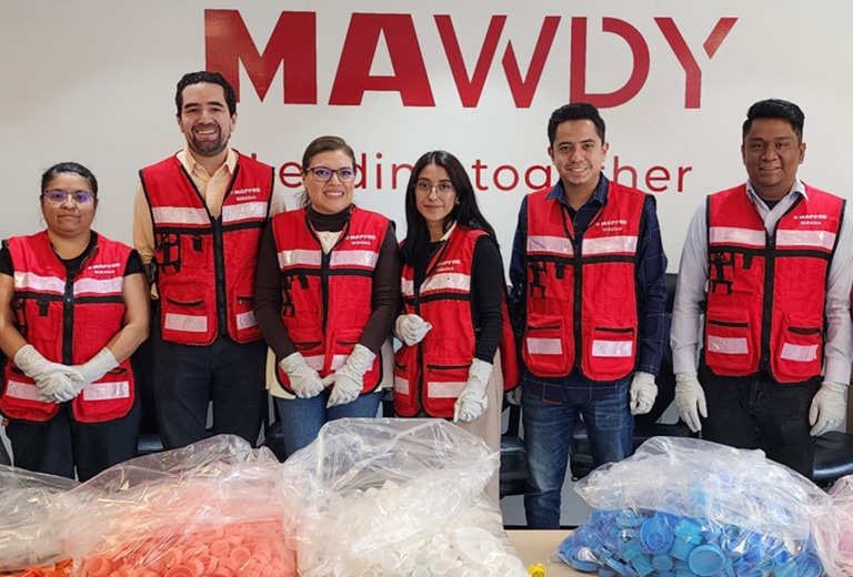 Voluntariado Voluntarios de Fundación Mapfre México con chalecos rojos clasificando tapones de plástico para reciclaje