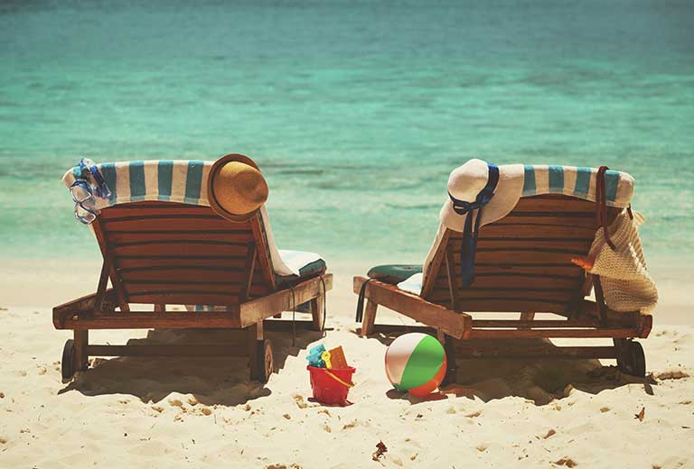 Claves para un verano seguro y saludable en familia Tumbonas en la playa con sombreros junto al mar durante las vacaciones de verano